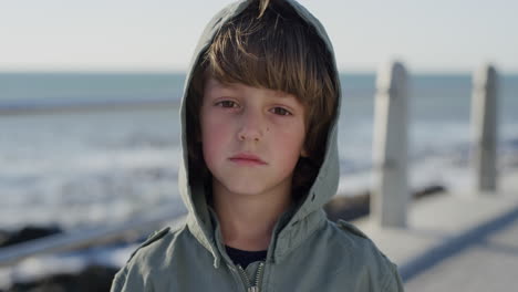 close up portrait serious little boy looking unhappy child caucasian kid on seaside slow motion