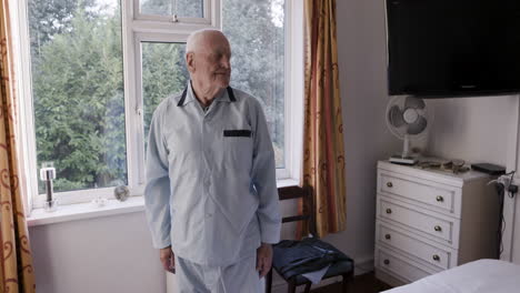 elderly man in pajamas by window