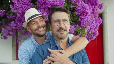 tiro medio de gays felices de pie y abrazándose en el jardín de verano mientras miran lejos