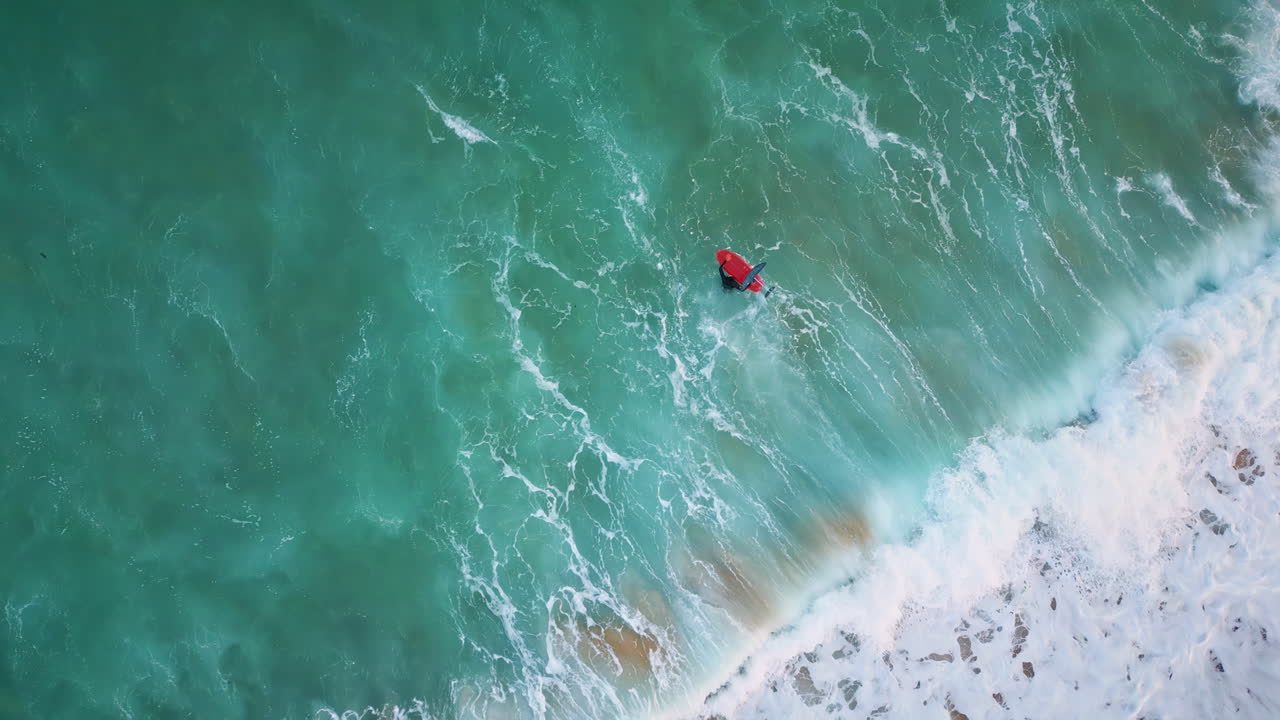 뷰 서퍼가 서프보드 위에서 수영을 하고 거품 같은 바다에서 물결을 흔들고 있다.