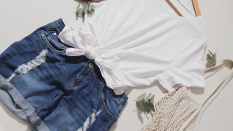 video of white t shirt, denim shorts, hat, bag and copy space on white background