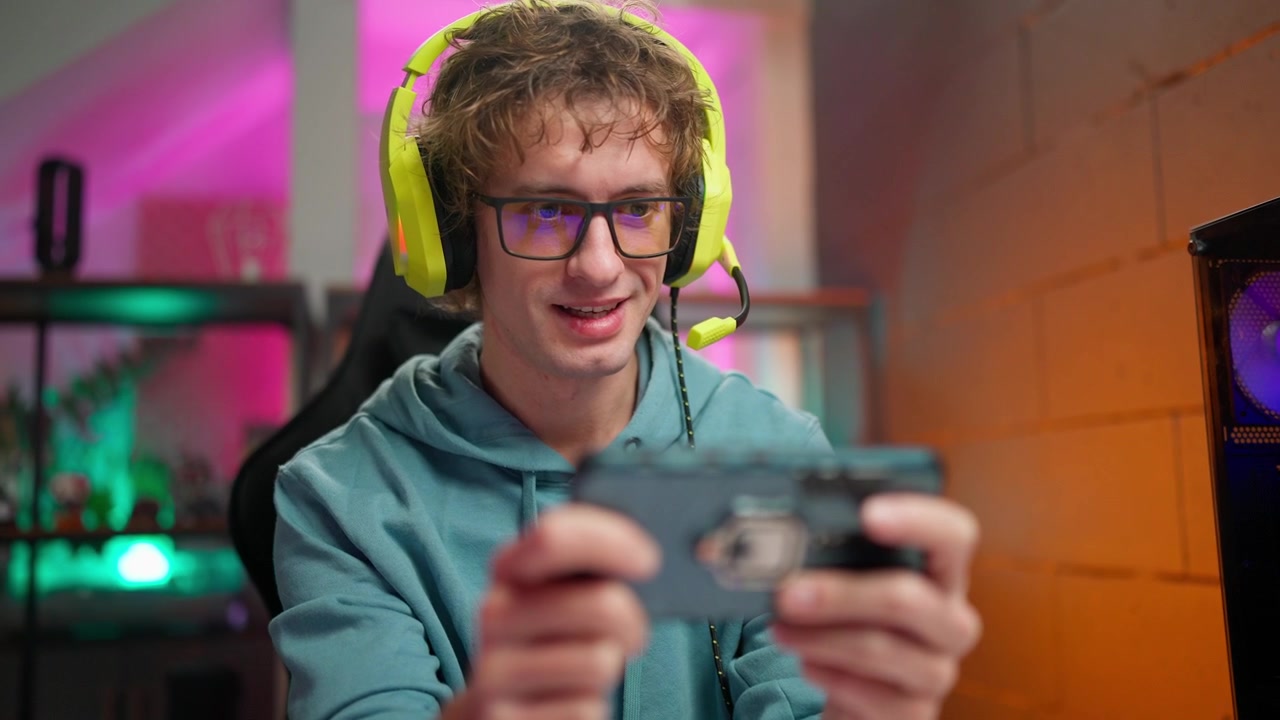 Giovane uomo che gioca a un gioco mobile e parla con le cuffie