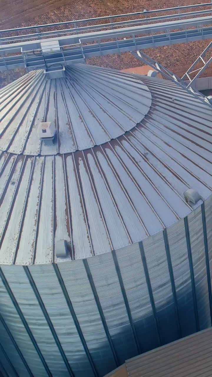 Special grain elevators for crop storage. Metal bridge from the roof of metal tank. View from above. Video from the top. Closeup. Vertical video