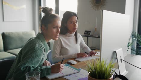 Focus-two-women-working-and-analyzing-something-on-computer-at-home