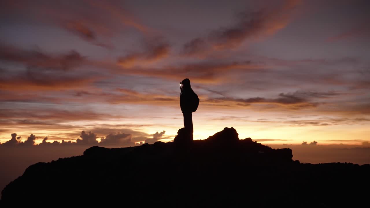 silueta de excursionista con faro en la cumbre del monte rinjani en indonesia en la isla de lombok en el colorido amanecer rosa púrpura