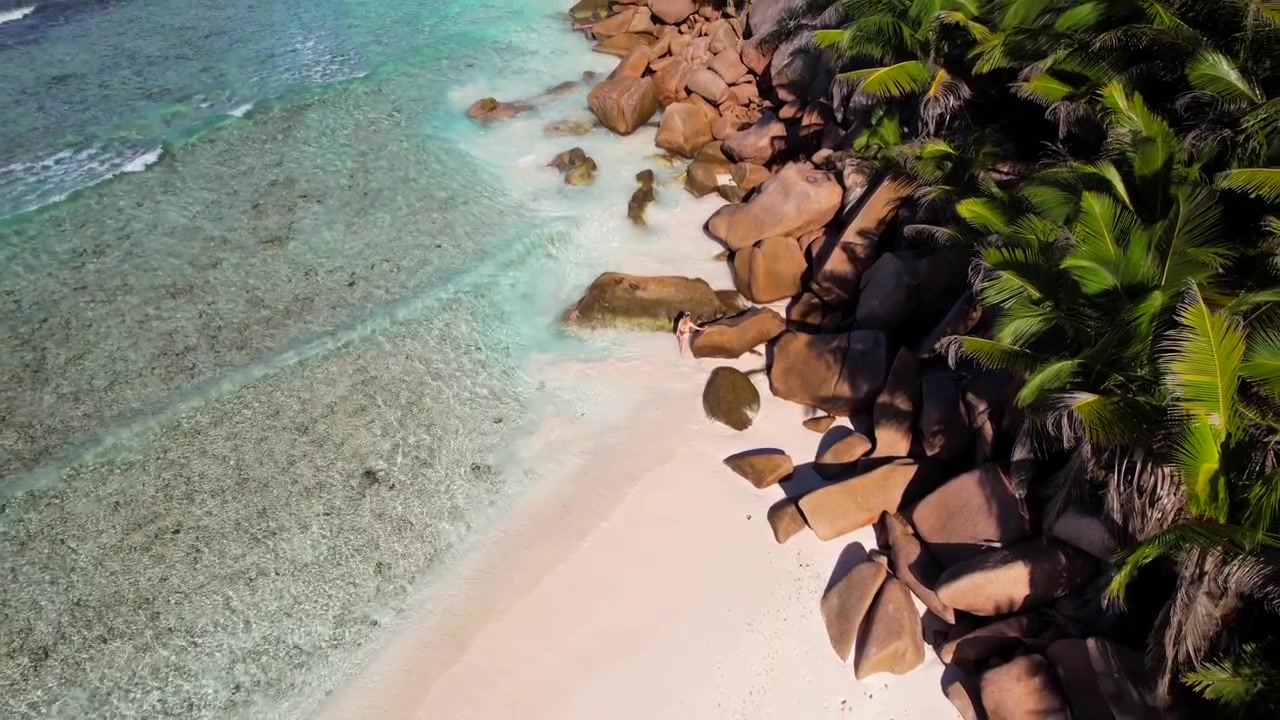 Wanita menjelajahi pantai terpencil di La Digue, Seychelles. Udara