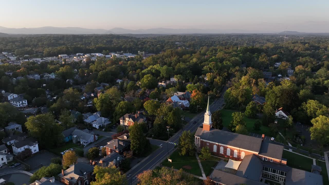 Aerial establishing shot of quaint american town with historic church. Autumn season with colorful trees in center with main street in USA. Drone orbit wide shot.