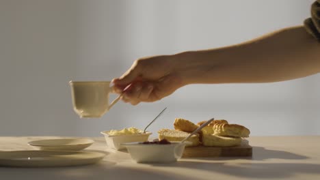 fotografía de estudio de una persona con el tradicional té de la tarde británico con crema de bollos y mermelada 1