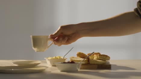 studio shot of person with traditional british afternoon tea with scones cream and jam 1