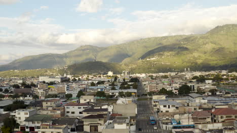 aerial view of a city nestled against mountains under a cloudy sky