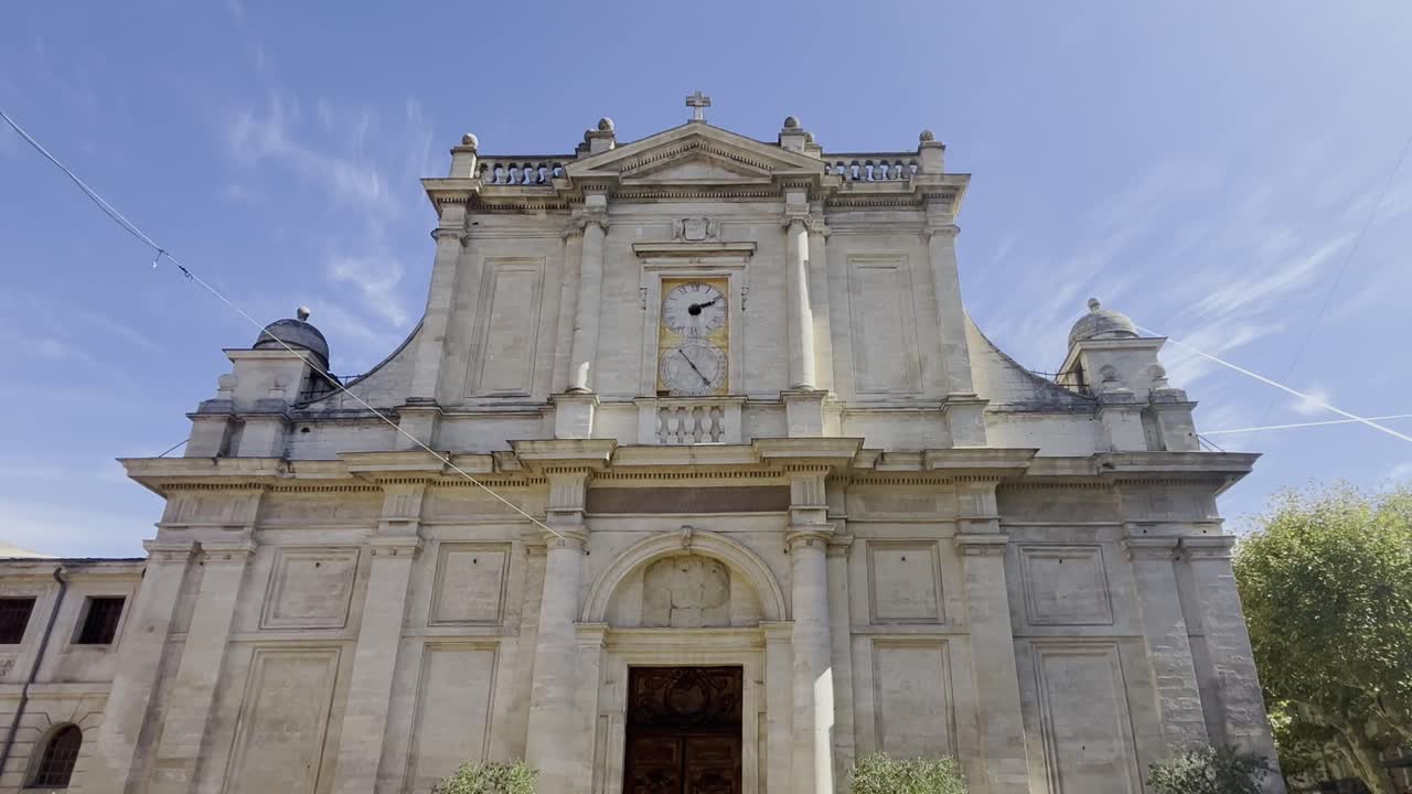 프랑스의 한 도시에서 많은 기둥과 오래된 시계가 있는 모래돌로 만든 오래된 시대적 교회 건물을 확대합니다.