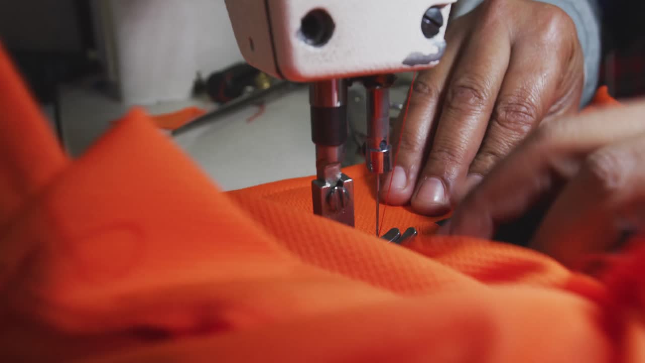 Mixed race woman using sewing machine in factory