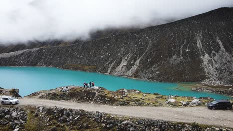 toma de drones de amigos junto a un lago turquesa en las montañas nubladas de yungay peru