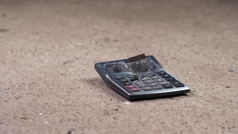 Hammer-smashing-already-broken-calculator-on-stone-floor,-Slow-Motion-Closeup