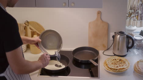 man pours pancake batter in pan and fry pancakes