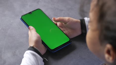 niño mirando un teléfono inteligente con una pantalla verde