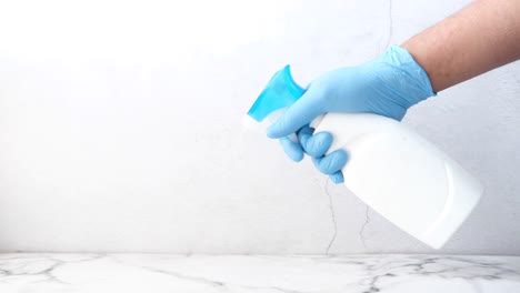 hand in blue gloves holding a spray bottle