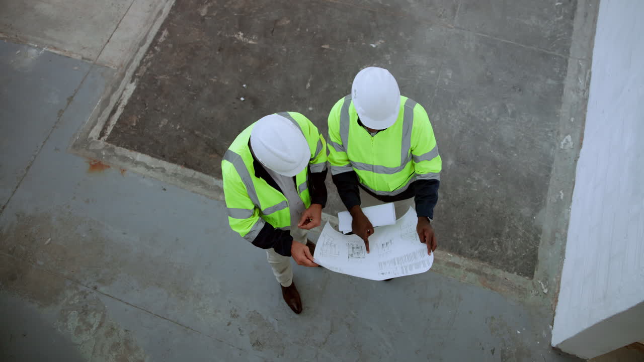 Construction workers reviewing blueprints on site