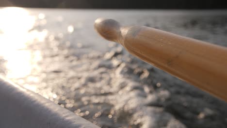 Blurry-atmospheric-water-with-paddle-in-foreground-and-blurry-background-of-a-lake-and-sunny-evening