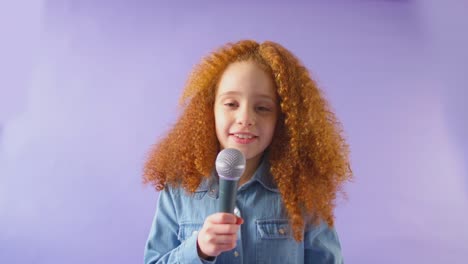 studio shot of girl singing karaoke into microphone against purple background - shot in slow motion
