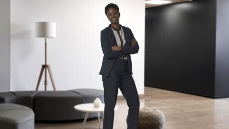 portrait of smiling businesswoman wearing suit standing in modern open plan office