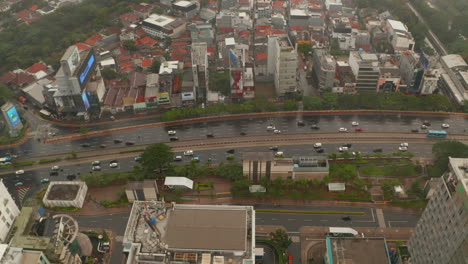 Aerial-dolly-tilting-shot-closing-in-on-multi-lane-highway-in-urban-city-center-on-a-rainy-day