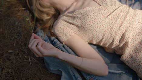 woman-holding-flower-lying-on-ground-in-forest-woods