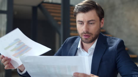 hombre de negocios serio mirando diagramas en la oficina. hombre enfocado leyendo documentos.