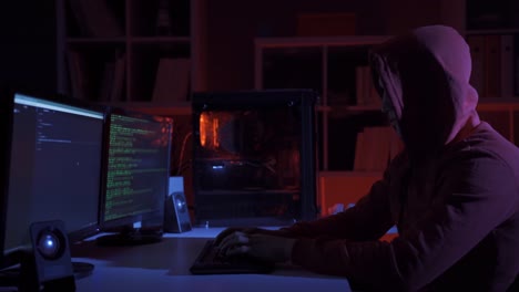 Side-view-of-hacker-sitting-near-computer-monitors-with-green-code-screens.