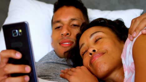 Couple-using-mobile-phone-while-relaxing-on-bed-4k