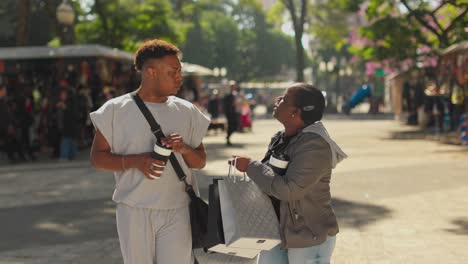 two people walking, drinking coffee, and shopping outdoors