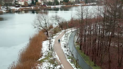 a man walking along a path in a park by a frozen lake