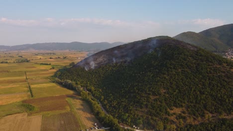 Aerial-approaching-burning-forest-above-agricultural-fields