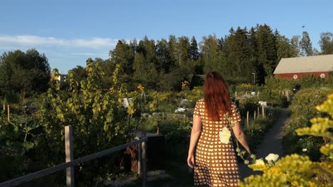 woman walking flower garden path to barn at countryside