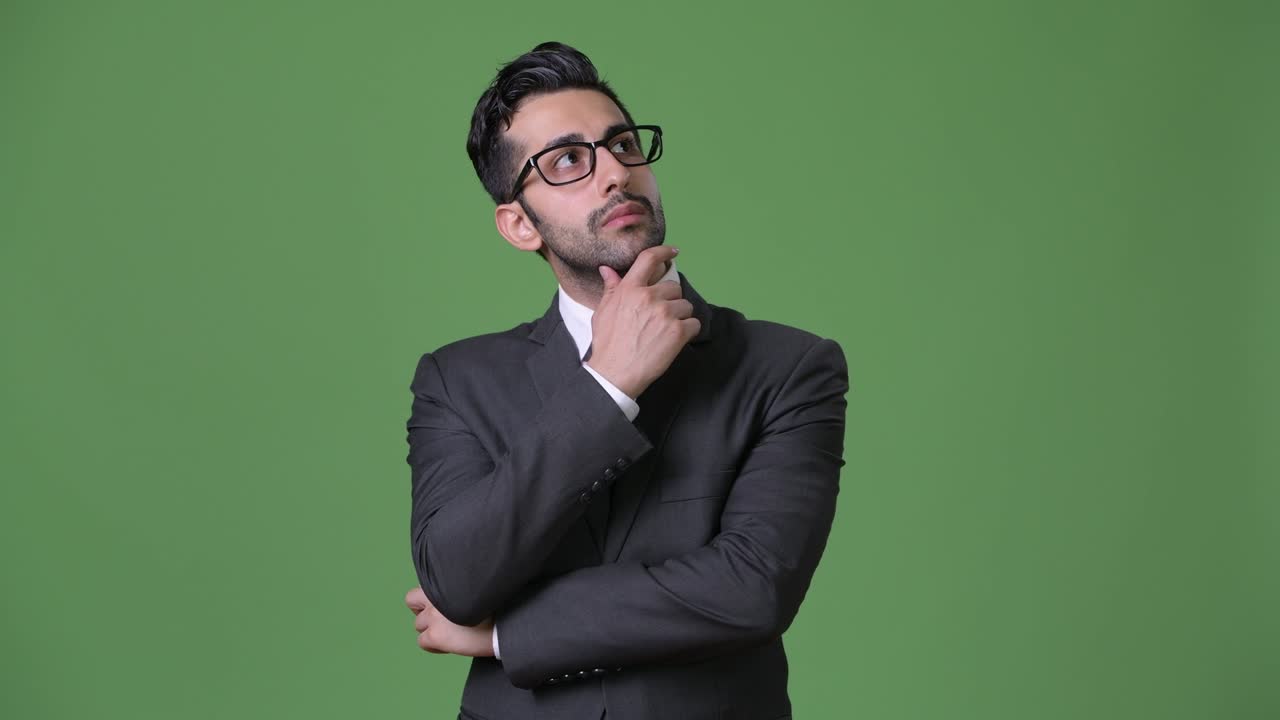 joven empresario persa barbudo y guapo contra un fondo verde