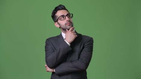 joven empresario persa barbudo y guapo contra un fondo verde