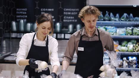 happy workers in a black apron sort products and put them on a rack. work in the store. weekdays. healthy food