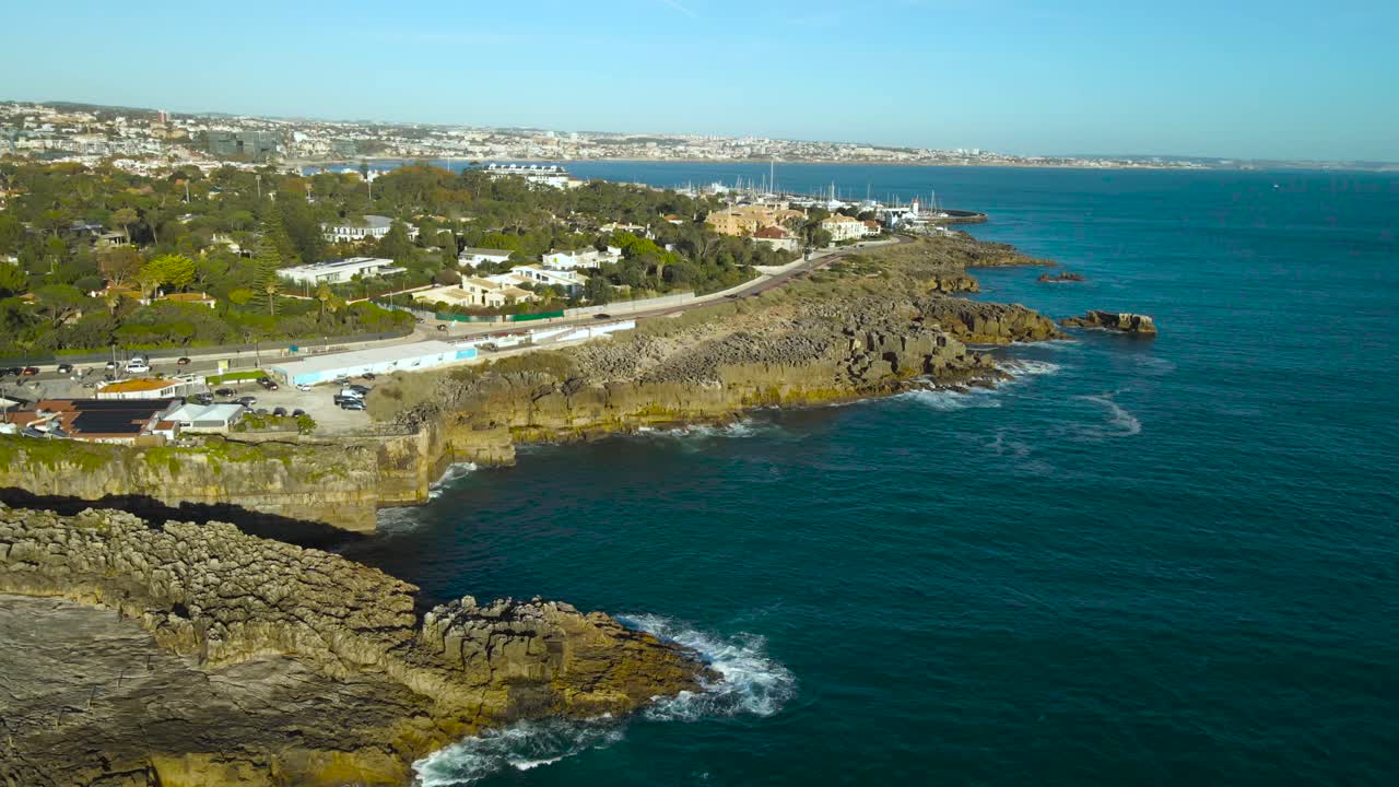 Aerial drone video flying in front of steep and sharop rocky karst fields and cliffs at Cascais Atlantic ocean seaside shoreline during sunny day at Campos de Lapias view point. Large waves hit cliffs