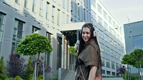 mujer caminando por la ciudad con auriculares y café