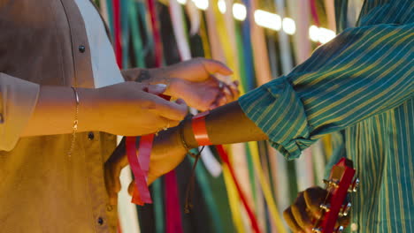 una mujer se pone una pulsera a un hombre.