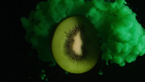 explosion effect of colors on a kiwi frying in the air on a black background. concept: fruit, colors, special effect