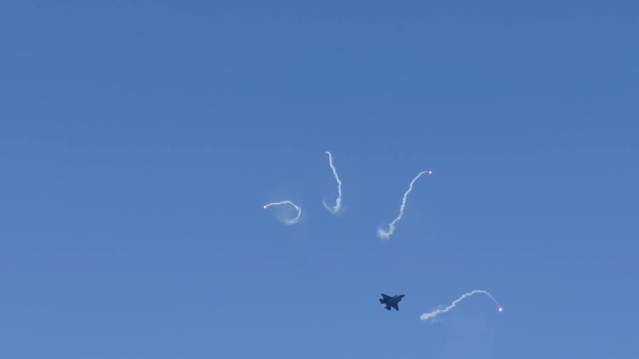 Jet da combattimento che rilascia flare ed esegue manovre nel cielo blu sopra la Gold Coast, Australia.
