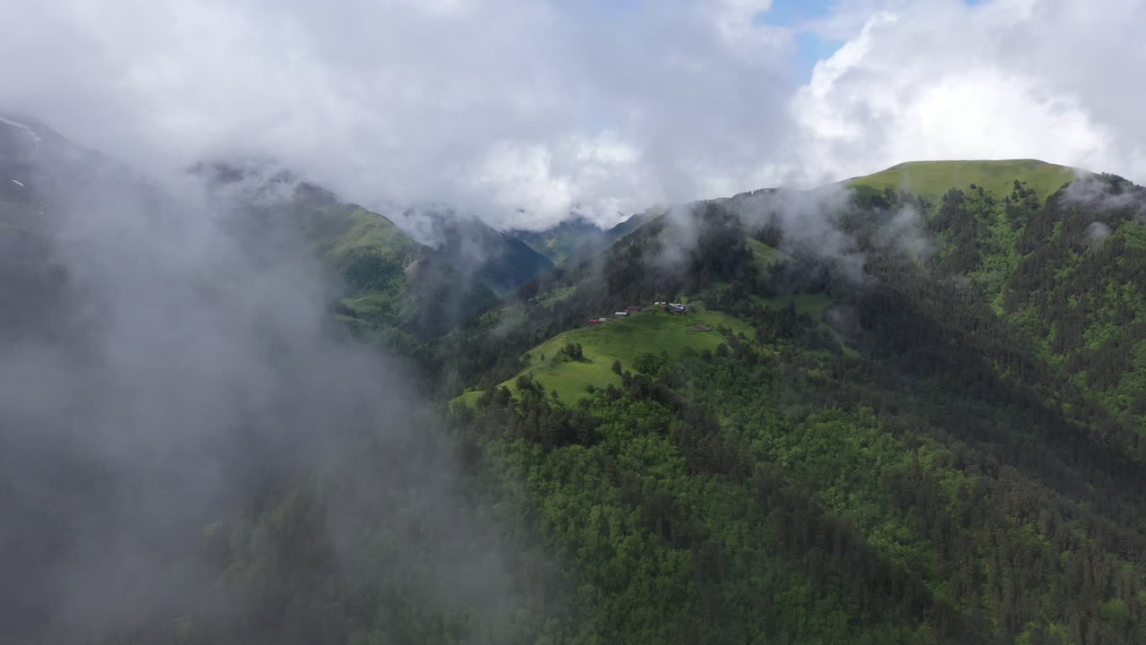 un gran dron disparó a través de las nubes de un pequeño pueblo en la cima de una montaña en el pueblo de tusheti en georgia