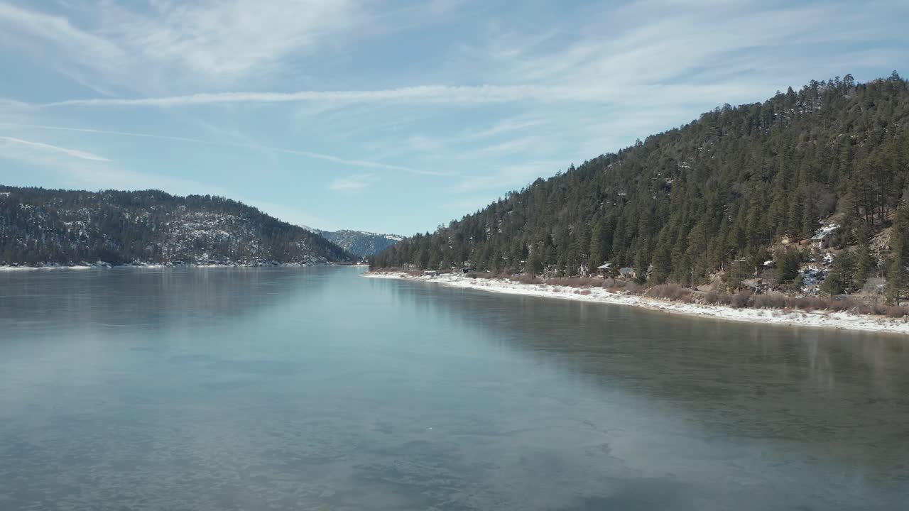 Low flying shot along the coast line of a frozen lake. 4K