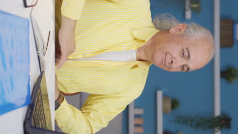 Vertical-video-of-Home-office-worker-old-man-attending-online-business-meeting.