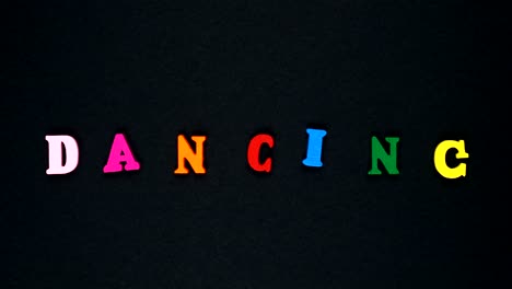 word "dancing" formed of wooden multicolored letters. colorful words loop.