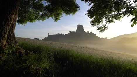 Corfe-Castle-at-sunrise-with-mist,-slow-panning-shot