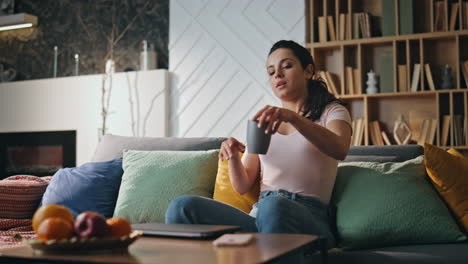mujer de negocios terminar el trabajo en línea sentado en el sofá de casa tomando café. chica relajada