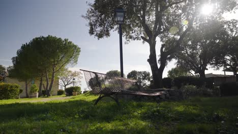 scenic shot of a bench in a park with sunlight coming out of the trees