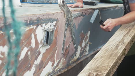 rolling grey primer onto hull of mahogany planked boat